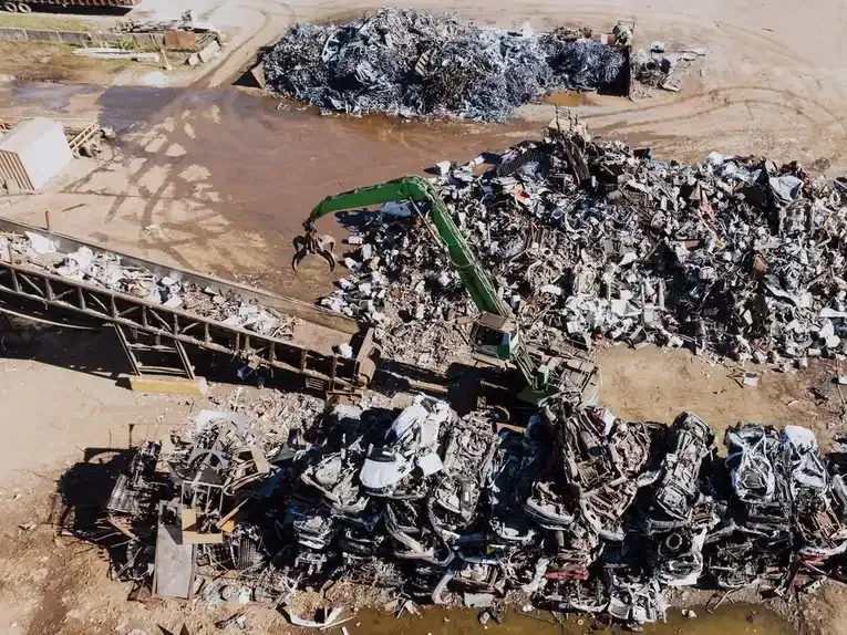 A view over a scrap yard showing the grab crane and sorted piles of metal.