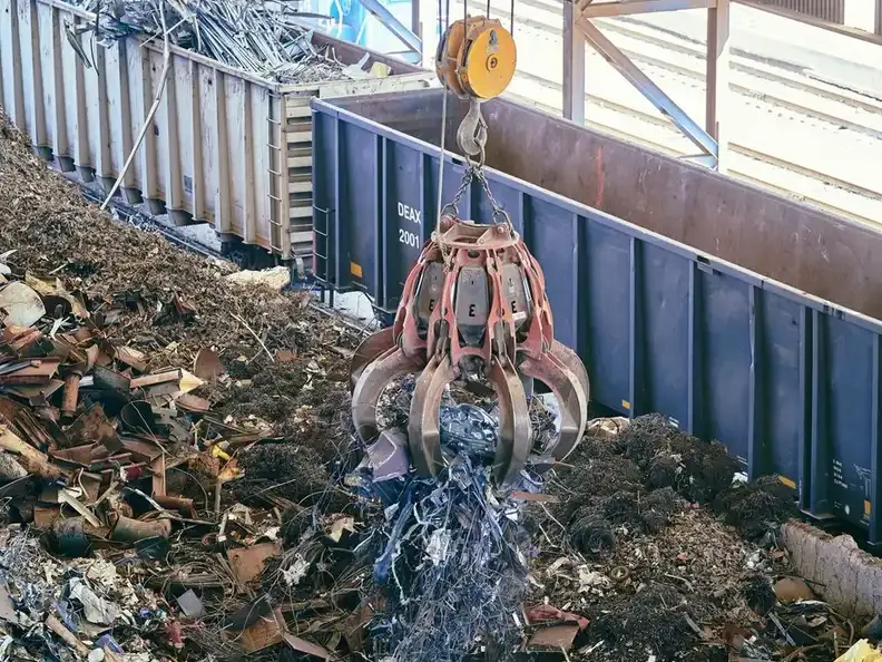 A grab crane loading scrap steel into a container.