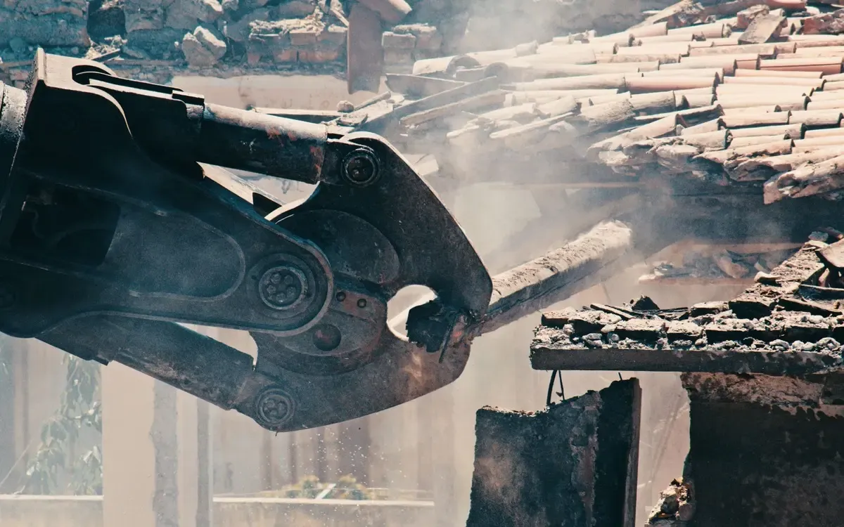 A demolition grab cutting through structural material on site.